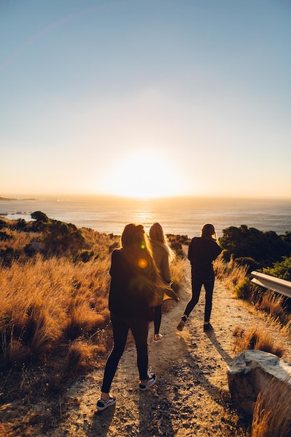 Hintergrundansicht von Freunden, die bei Sonnenuntergang am Strand vor klarem Himmel spazieren gehen