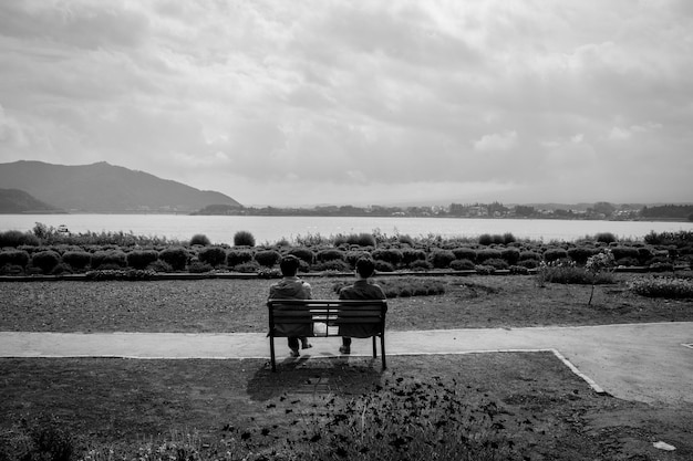Hintergrundansicht von Männern, die am Strand am See gegen den Himmel sitzen