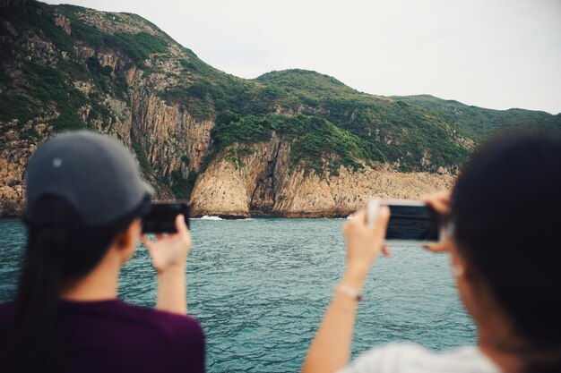 Foto hintergrundansicht von menschen, die das meer gegen einen klaren himmel fotografieren