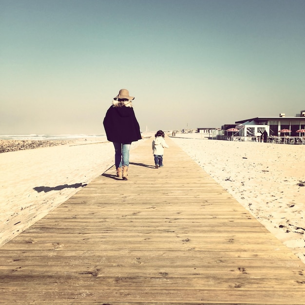 Hintergrundansicht von Mutter und Tochter auf der Promenade am Strand gegen den Himmel