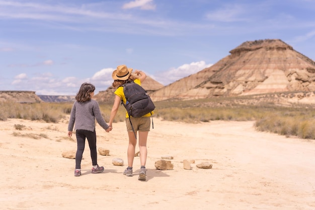 Hintergrundansicht von Mutter und Tochter, die in einem trockenen Nationalreservat entlang einer Wüste spazieren gehen