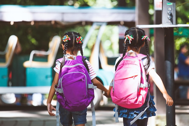 Hintergrundansicht von Schulmädchen, die Rucksäcke tragen, während sie auf der Straße laufen