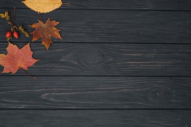 Hintergrundbeschaffenheit mit altem Holztisch und gelben herbstlichen Blättern. Draufsicht