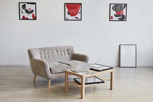 Hintergrundbild des Designerinnenraums mit Couch und Couchtisch verziert durch moderne abstrakte Gemälde an der Wand,
