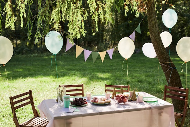 Hintergrundbild des Sommer-Picknick-Tisches im Freien mit Luftballons für Geburtstagsfeier-Kopienraum dekoriert