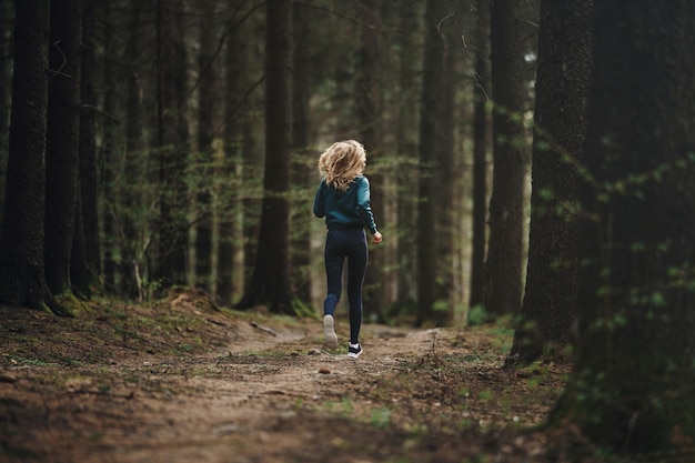 Hintergrundbild in voller Länge einer Frau, die im Wald rennt