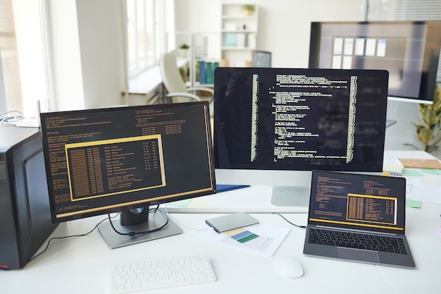 Hintergrundbild mehrerer Computerbildschirme mit Codezeilen auf dem Schreibtisch im Büro der IT-Entwickler, Kopierbereich