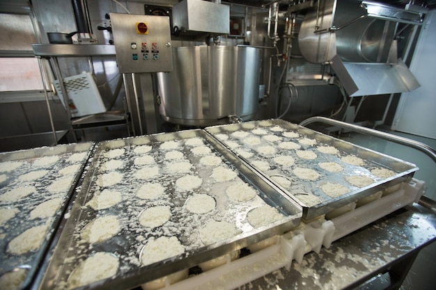 Hintergrundbild von rohem Käsequark in Formen am Förderband der industriellen Lebensmittelfabrik, Kopierraum