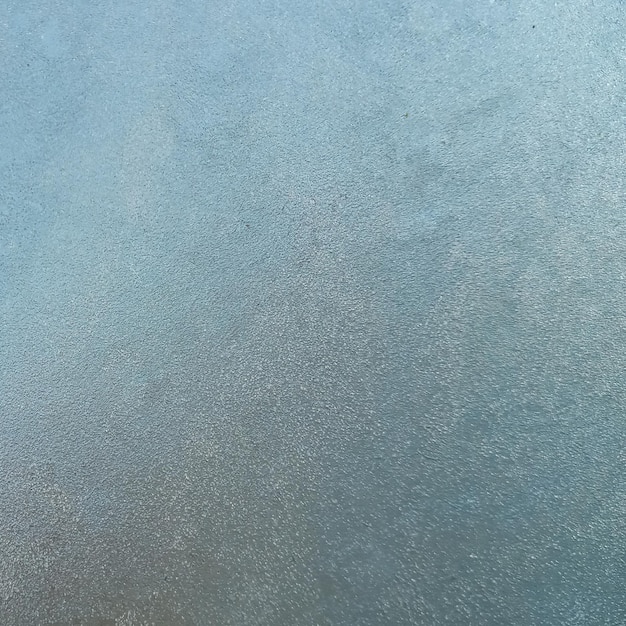Hintergrundtextur Gefrorenes Glas mit einsetzender Kälte. Blick durch die Eisschicht des blauen Himmels