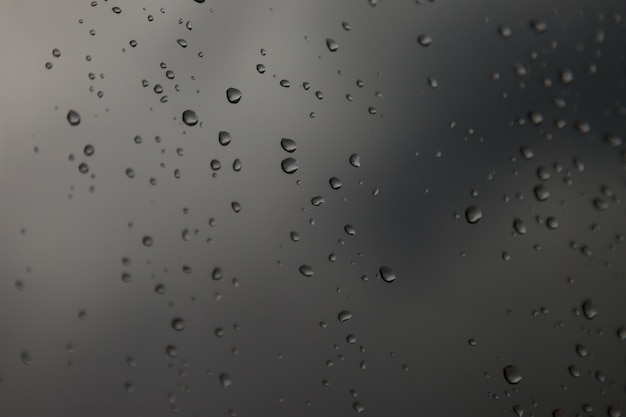 Hintergrundwassertropfen. Regentropfen auf Fensterscheiben. Natürliches Muster von Regentropfen. Abstrakter Schuss von Regentropfen auf Glas. Abstrakter fallender Regentropfen des Regens auf Glas. Platz für eine Inschrift oder ein Logo