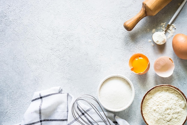 Hintergrundzutaten zum Backen, Mehl, Zucker, Eier und andere am hellen Steintisch, Draufsicht mit Kopierraum
