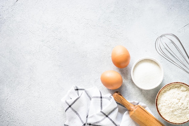 Hintergrundzutaten zum Backen, Mehl, Zucker, Eier und andere am hellen Steintisch, Draufsicht mit Kopierraum