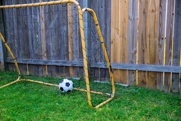 Hinterhof chldren Fußball am hölzernen Zaun mit Wand