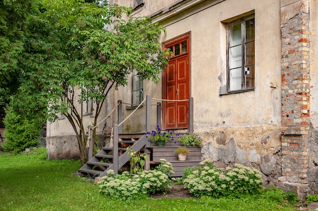 Hinterhofansicht des alten Hauses mit Holzstufen und grünem Rasen.