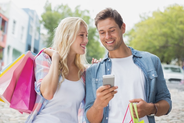 Hip jovem casal olhando smartphone na viagem de compras