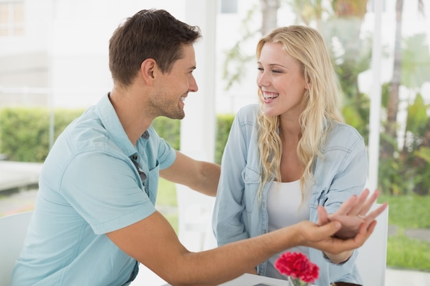 Hip jovem casal sentado à mesa, sorrindo um para o outro