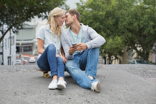 Hip jovem casal sentado no skate beijando