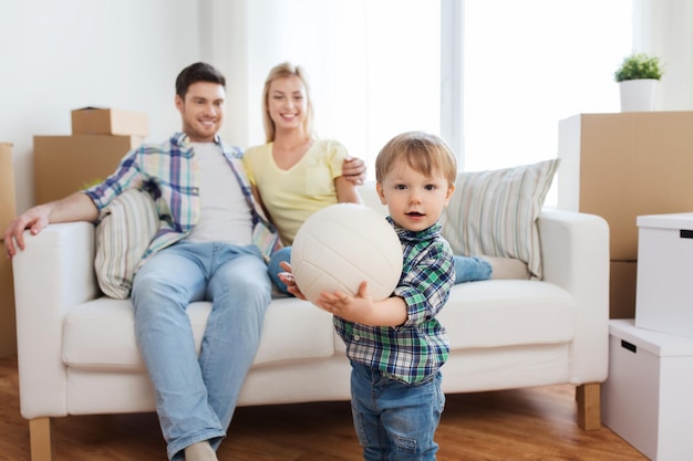 hipoteca, gente, vivienda, mudanza y concepto de bienes raíces - niño feliz con pelota sobre los padres en casa