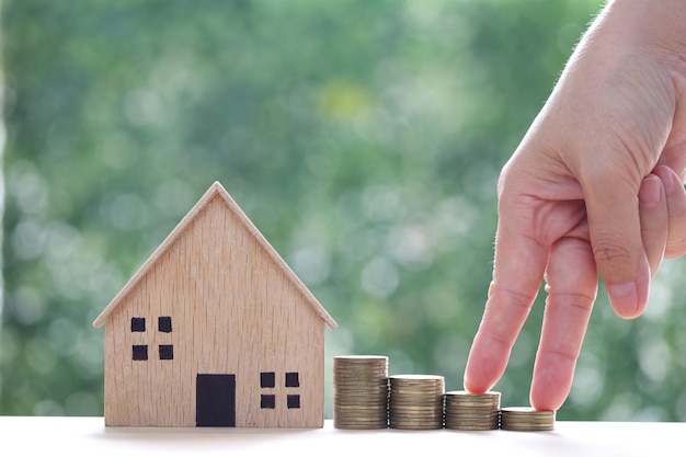 Hipoteca Modelo de casa y pila de monedas dinero en un fondo verde natural Inversión empresarial y concepto inmobiliario