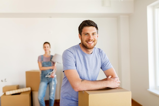 Foto hipoteca, personas y concepto de bienes raíces - pareja feliz con cajas moviéndose a una nueva casa