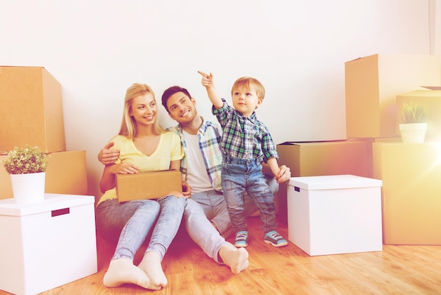 Foto hipoteca, personas, vivienda y concepto de bienes raíces - familia feliz con cajas que se mudan a un nuevo hogar
