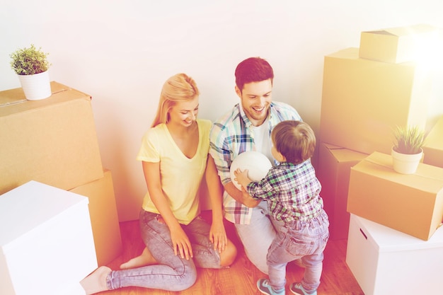 Foto hipoteca, pessoas, habitação, mudança e conceito imobiliário - família feliz com caixas jogando bola na nova casa