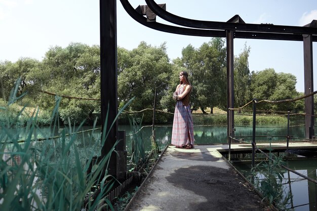 Hippie-Frau, die am Sommertag auf Holzbrücke steht.