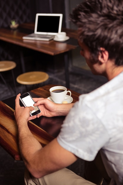 Hippie-Mann, der Smartphone beim Trinken des Kaffees verwendet