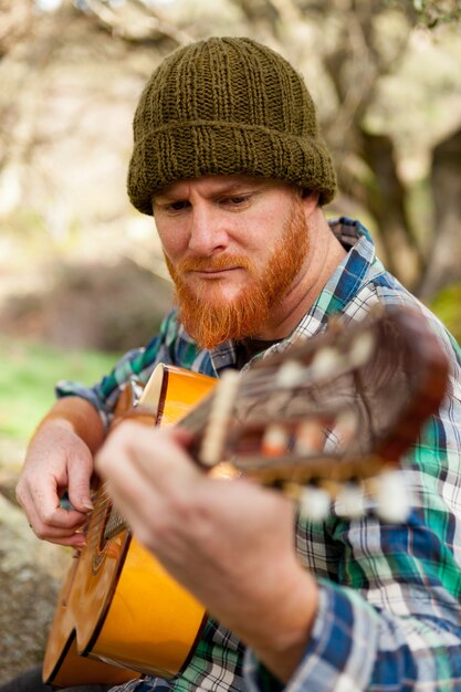 Hippie-Mann mit dem roten Bart, der eine Gitarre spielt