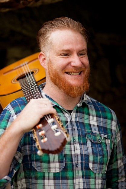 Hippie-Mann mit rotem Bart mit einer Gitarre