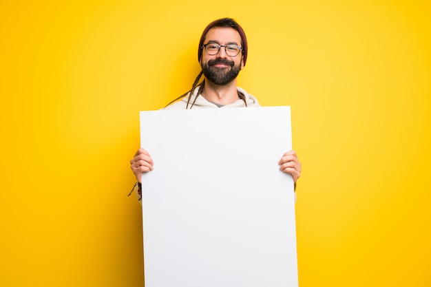 Hippiemann mit den Dreadlocks, die ein leeres Plakat für Einfügen ein Konzept halten