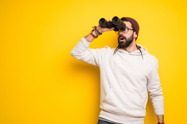 Hippiemann mit Dreadlocks und Fernglas mit Fernglas schauen