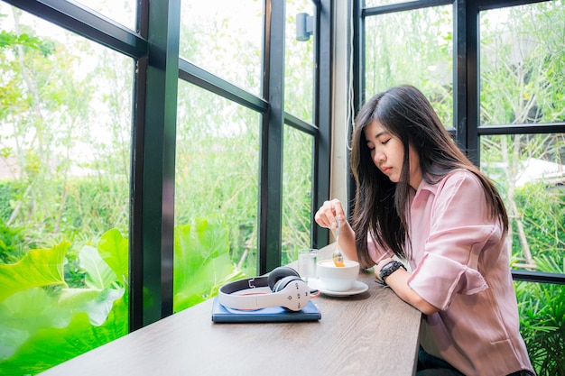 Hipster adolescente da Ásia pensando sozinho no café Mulher na parte traseira sentada