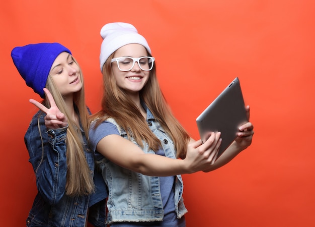 Hipster amigas tomando selfie con tableta digital, estudio