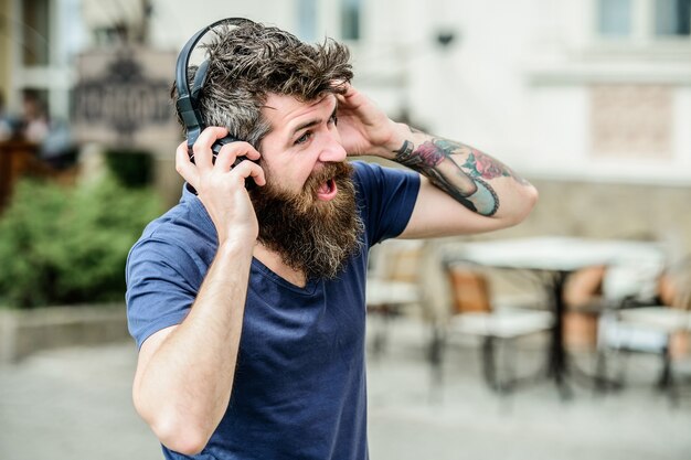 Hipster aproveite uma excelente música de som em fones de ouvido. Caminhando com música. A batida da música para um clima energético. Ritmo de caminhada. Homem barbudo hipster fones de ouvido ouvindo música. Excelente lista de reprodução de música.