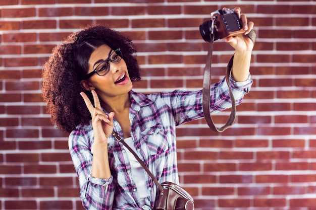 Hipster atraente que toma selfies com câmera