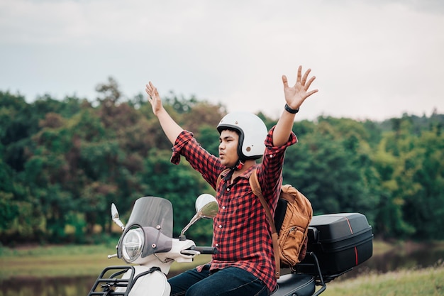 Foto hipster backpacker mit einem motorroller auf der straße reisen mit dem roller langsames leben im urlaub ruhezeit