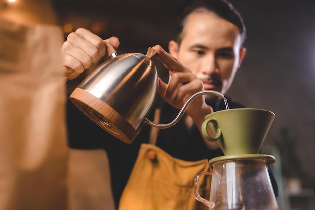 Hipster-Barista gießt ein heißes Wasser zur Kaffeezubereitung mit Tropf- oder Filterstil im Café Slow Brew für Koffein-Aroma-Getränk in Tasse frischen schwarzen Kaffee und Espresso zum Frühstück