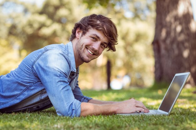 Hipster bonito usando laptop no parque