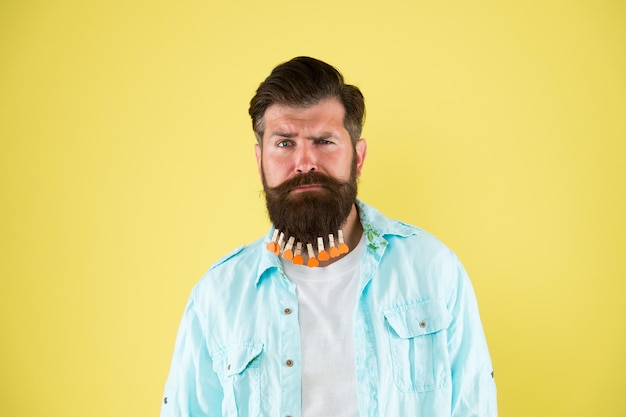 Hipster brutal hip e elegante com corações de prendedor de roupa homem barbudo estilo casual fundo amarelo dia dos namorados secagem de cabelo no cabeleireiro penteado individual para prendedor de roupa masculino na barba