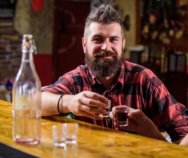 Hipster brutaler bärtiger Mann verbringen Freizeit mit Freund an der Theke Männer entspannen an der Bar Starke Alkoholgetränke Freitagsentspannung in der Bar Freunde entspannen in der Kneipe Cheers-Konzept Lasst uns betrinken