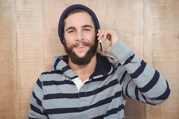 Hipster con camisa con capucha utilizando teléfono móvil