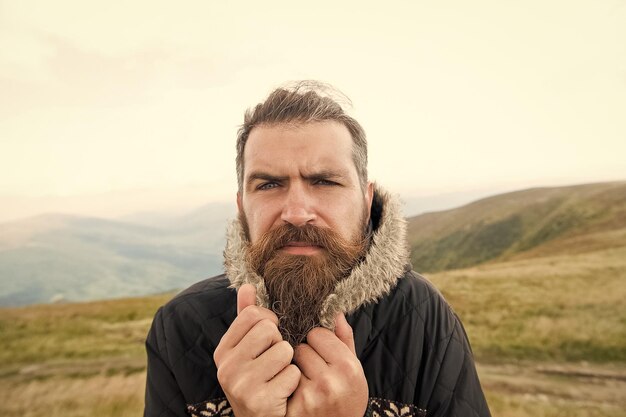 Hipster caucasiano brutal de homem barbudo com bigode frio na montanha