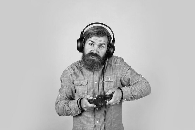 Hipster caucasiano com barba e cabelo elegante em fone de ouvido com vida moderna de console de jogos