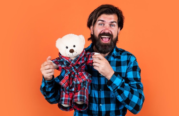 Hipster caucasiano de homem barbudo com barba longa em camisa xadrez e ursinho de pelúcia marrom bonito para presentes e presentes de dia dos namorados