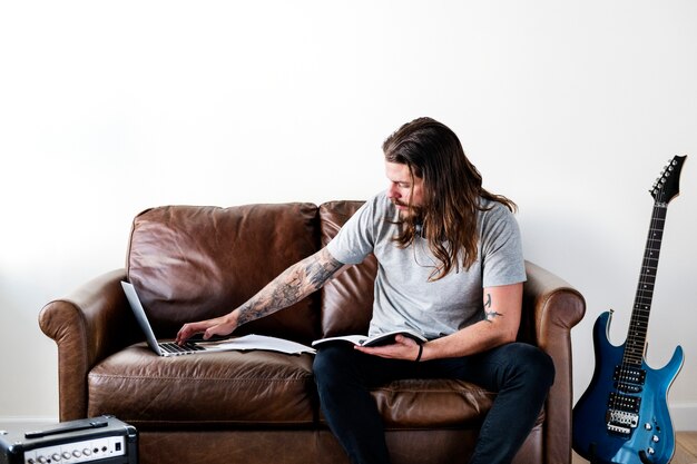 Hipster caucásica rockero trabajando en una computadora portátil