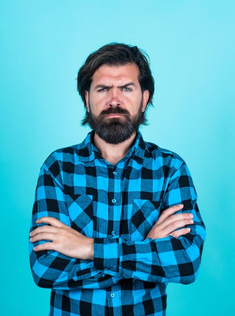 Hipster caucásico serio con cabello moreno con barba y bigote perfectos manos cruzadas barbero