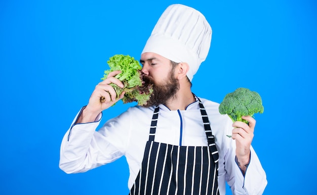 Hipster-Chefkoch veganes Café Gesundheit und Diät Ich wähle veganen Lebensstil Mann Kochmütze Schürze halten Brokkoli und Salat Veganes Rezeptkonzept Kaufen Sie frisches Gemüse Lebensmittelgeschäft Veganes Restaurant