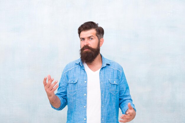 Hipster com barba e bigode usar camisa jeans Conceito de beleza masculina Homem hipster bonito brutal no fundo da parede cinza Homem barbudo na moda estilo hipster Salão de barbeiro Macho bem preparado