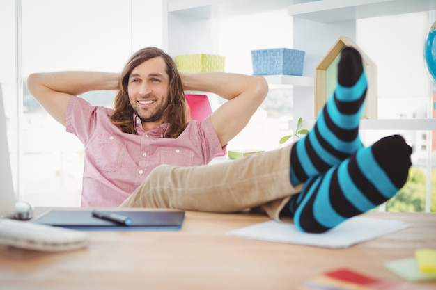 Hipster, der mit den Beinen auf Schreibtisch sich entspannt